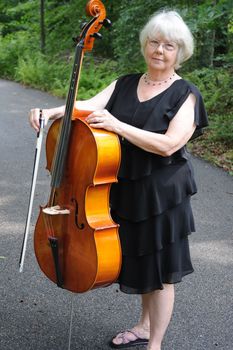 Female cellist standing outside with her cello.