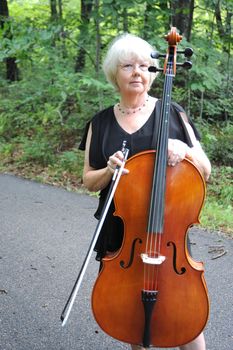 Female cellist standing outside with her cello.