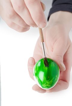 Woman decorating white egg with paint