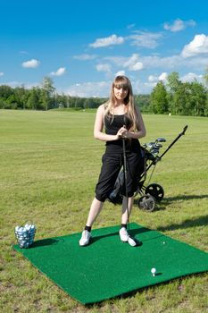 Woman about to strike golf ball on green field