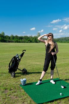 Woman about to strike golf ball on green field