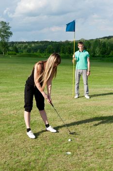 golf woman player green putting hole golf ball a man holding flag