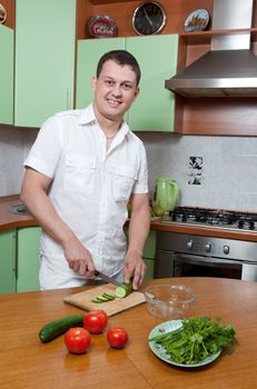 Young man preparing salad at the kitchen