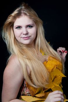 portrait girl in dress decorated with autumn leaves on black background