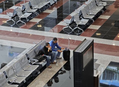 Two men waiting in airport departure lounge Ankara Esenboga Turkey, landscape with crop margins and empty spaces