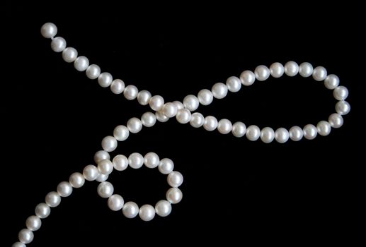 White pearls on the black velvet background 