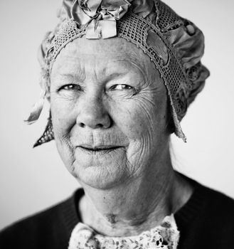 Senior smiling woman in the studio wearing a vintage hat and lace.