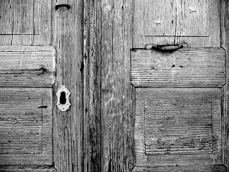 detail of an old weathered wooden door, keyhole, black white