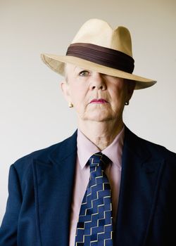 Dramatic senior woman in a man's suit wearing a straw gangster hat
