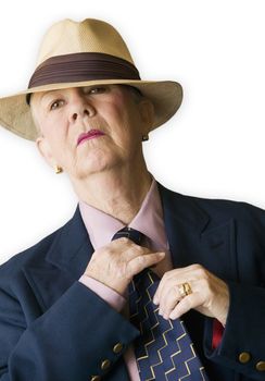 Woman wearing a man's hat and suit adjusting her tie.