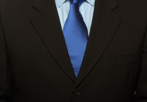 cropped shot of torso part of a man in black suit and blue tie