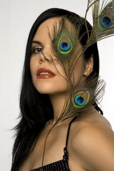 Attractive woman posing with peacock feather. Exquisite detail on feather