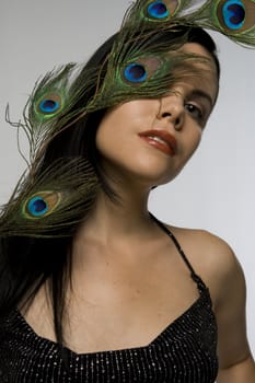 Attractive woman posing with peacock feather. Exquisite detail on feather