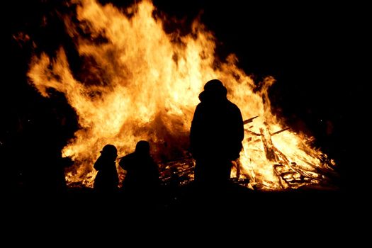 Siluette of a small family in front of a bonfire