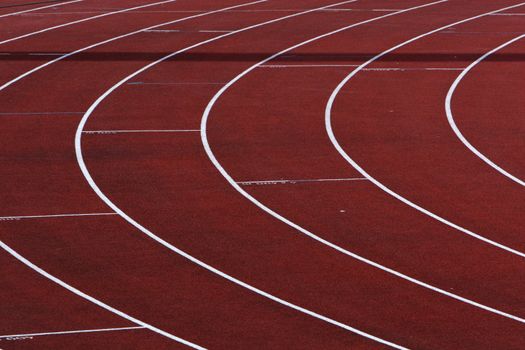 Curve on a red running track with white lines between the lanes