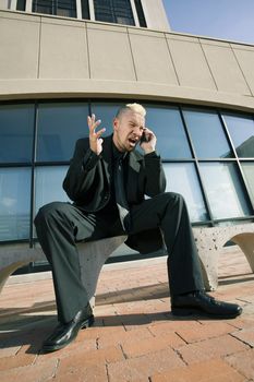 Businessman with a punk haircut shows frustration and anger regarding his cell phone.