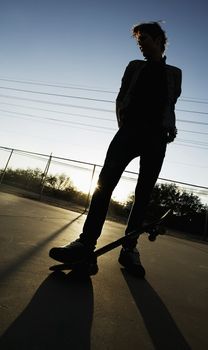 Teenage boy skateboarder with his board.