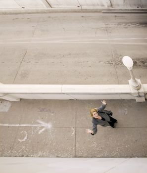 Wide shot from above of woman on a sidewalk with her hands in the air