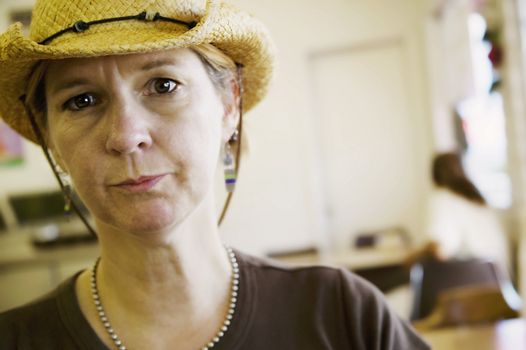 Woman indoors in a cowboy hat looks intently at the camera.