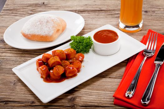 curry wurst spicy sausage with curry and ketchup on wooden background