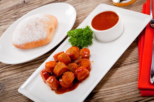 curry wurst spicy sausage with curry and ketchup on wooden background