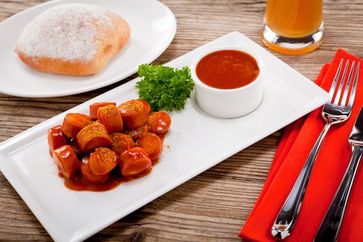 curry wurst spicy sausage with curry and ketchup on wooden background
