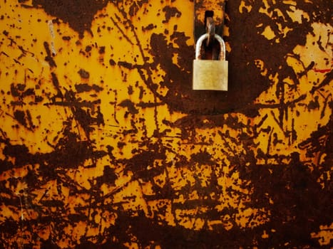 Old brass lock on steel plate filled with iron rust