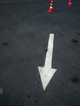 White arrow on the road and orange cone blocking the way