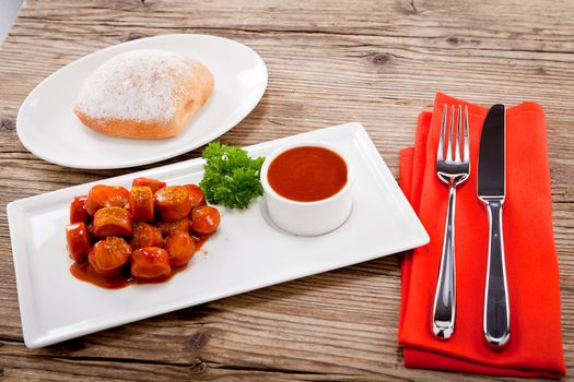 curry wurst spicy sausage with curry and ketchup on wooden background