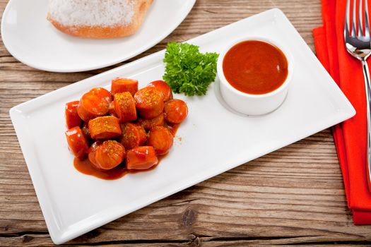 curry wurst spicy sausage with curry and ketchup on wooden background