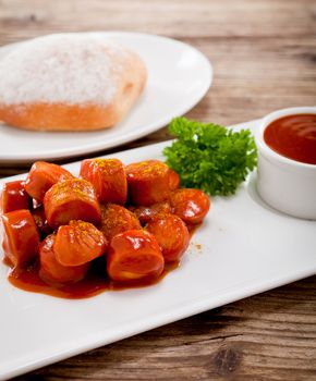 curry wurst spicy sausage with curry and ketchup on wooden background