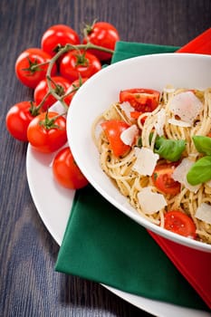 fresh tasty pasta spaghetti with tomatoes parmesan and basil on table