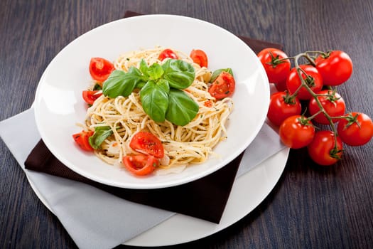fresh tasty pasta spaghetti with tomatoes parmesan and basil on table