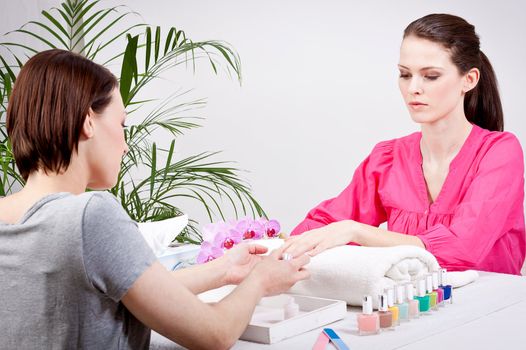 young brunette woman get manicure by professional in beauty salon 