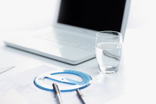 workplace, laptop and water glass on white table