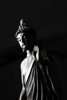 Partial view of a statue of Buddha on black background