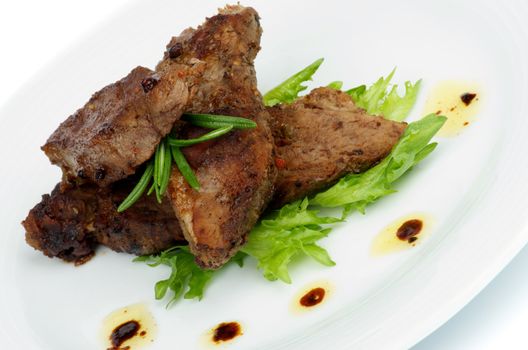 Roasted Beef with Spices, Peppercorns, Rosemary and Herbs closeup on White Plate with Lettuce