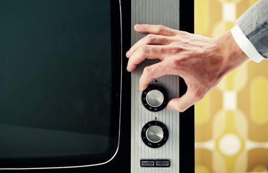 Man  turning channel knob on retro television 