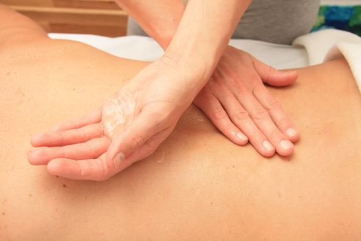 A female masseur preparing her hand with oil for a back massage