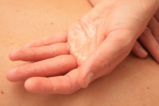A female masseur preparing her hand with oil for a back massage