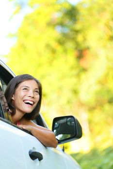 Car woman on road trip looking out of window smiling happy. Beautiful multicultural Asian Caucasian woman.