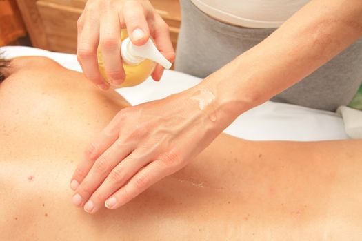 A female masseur preparing her hand with oil for a back massage