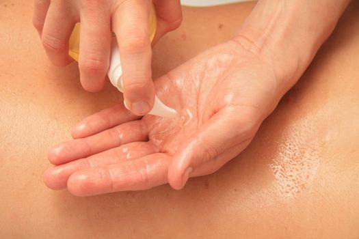 A female masseur preparing her hand with oil for a back massage