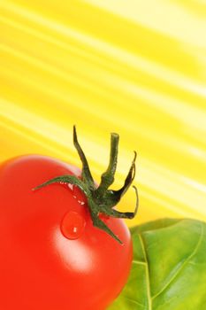 Tomato with drops and uncooked spaghetti noodleson background