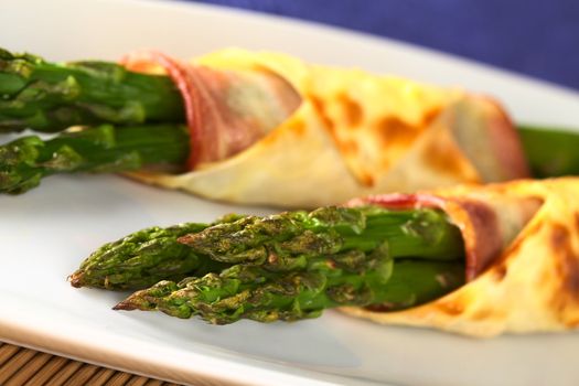 Baked green asparagus wrapped in bacon and wonton dough (Selective Focus, Focus on the asparagus tips in the front)