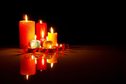 A lot of burning colorful candles against black background