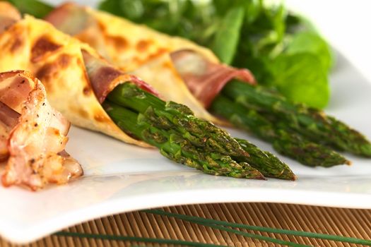 Baked green asparagus wrapped in bacon and wonton dough (Selective Focus, Focus on the two asparagus tips in the front)