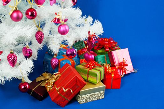 Heap of the Christmas presents under decorated white evergreen tree