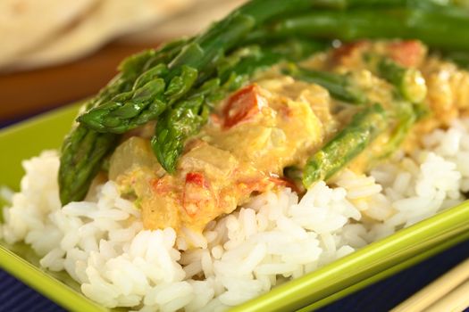 Green asparagus curry served on rice with chapati in the back (Selective Focus, Focus on the two asparagus tips in the front and on the top)