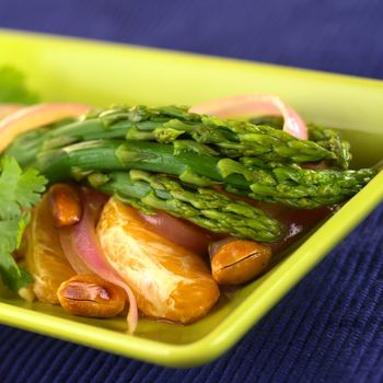 Green asparagus prepared in Thai-style with oranges, onions and peanut in an orange-ginger sauce (Selective Focus, Focus on the three asparagus heads in the front)